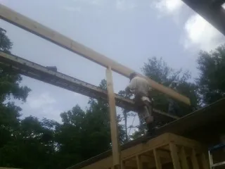 Carpenter setting a ridge beam over a new addition frame — Ice Dam Removal by Roofing Brothers in Glen